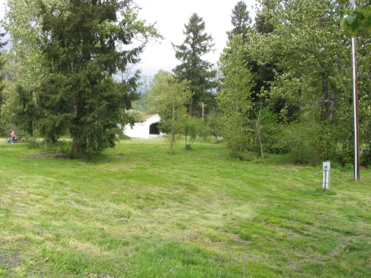 a grassy area with a sign next to some trees