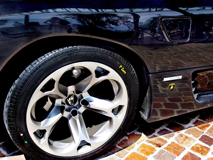 wheel and tires of a black car on a sidewalk