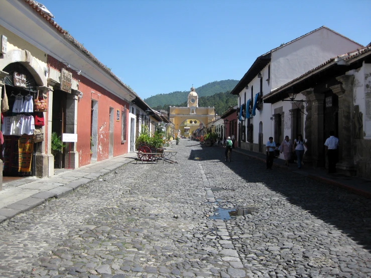 people walking down a cobblestone street next to buildings