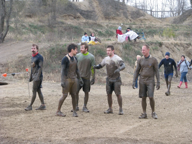 a group of men in mud suits with people lying on a hill