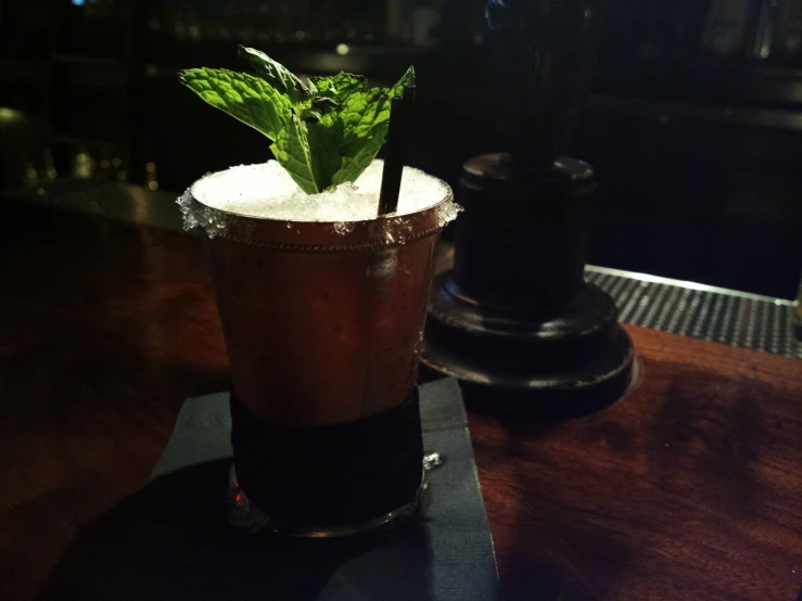 a glass of dark colored alcoholic drink on top of a table