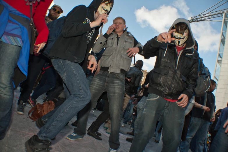 four people dressed in masks and jeans on a street