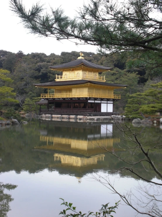 an oriental temple is reflected in a lake