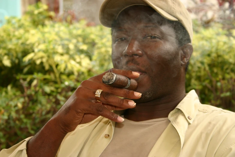 man wearing gold and white ring and gold band smoking cigar