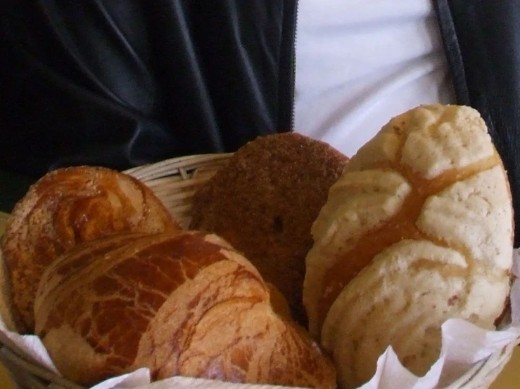 a basket full of croissants and pastries on a table