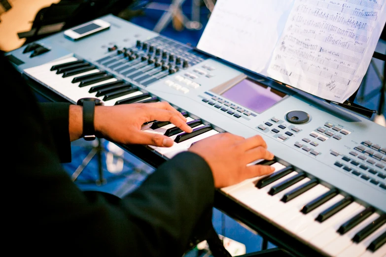 a man holding a keyboard in front of an electronic piano