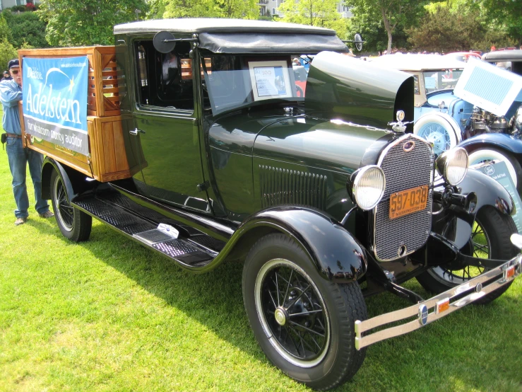 a man standing next to a truck parked on top of a green field