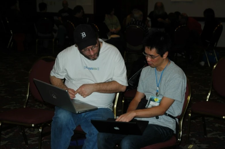 a man works on his laptop in front of another man