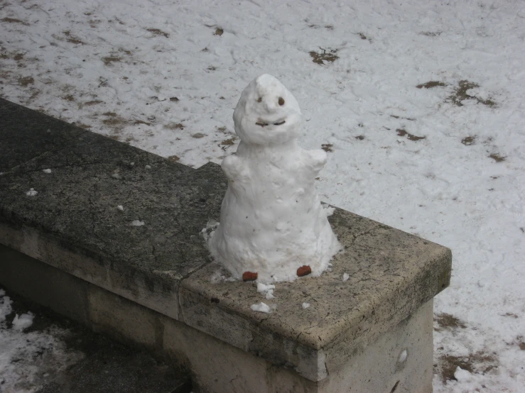 a snow man sitting on a stone bench