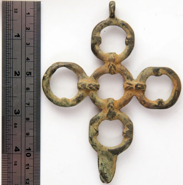 three bronze shaped key pieces on a measuring ruler