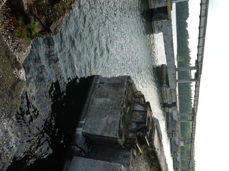 a view from a boat of an abandoned concrete structure next to a river