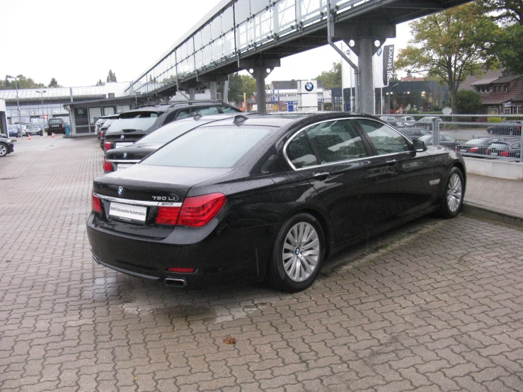 black bmw parked in front of a city street under a bridge