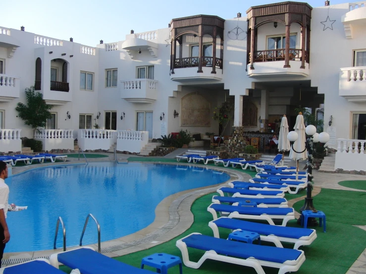 the apartment building has a swimming pool surrounded by lawn chairs