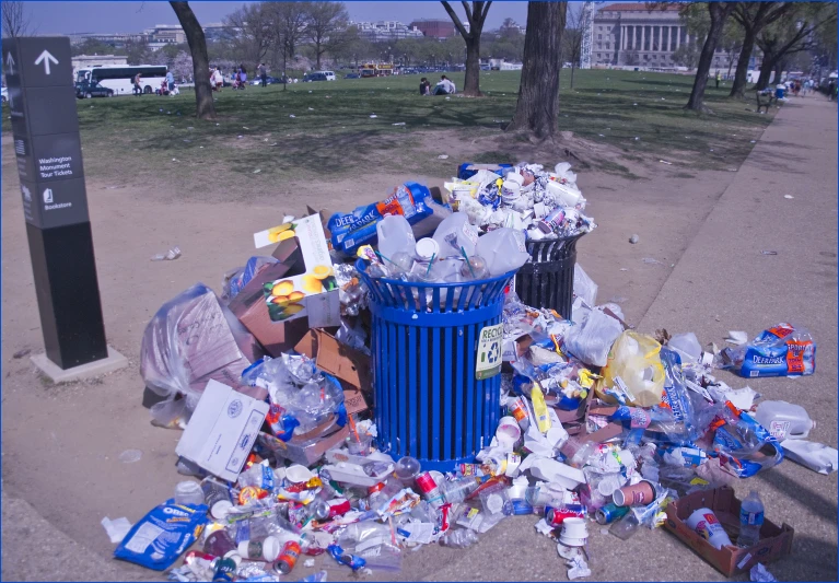 there is many trash piled high up by the road