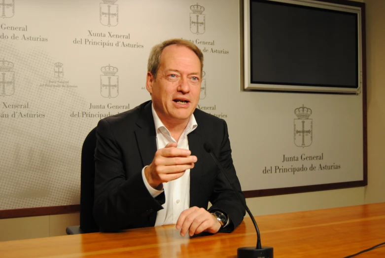 a man in a suit is at a meeting with an audience