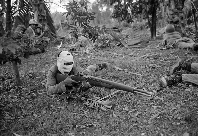 a soldier wearing a helmet with a gun in the grass