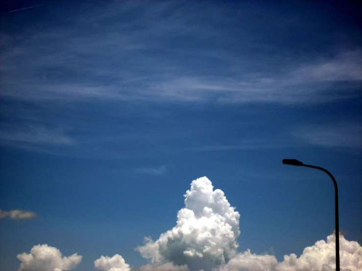 a street light next to a cloud on a blue sky