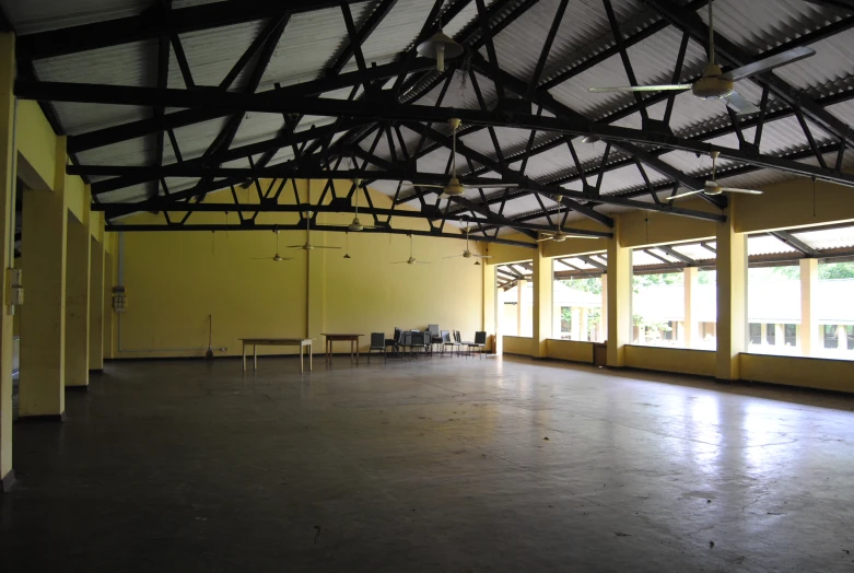 the large empty building has yellow walls and a row of benches