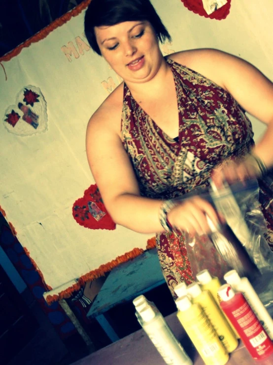 a woman preparing drink in a kitchen with a wooden table