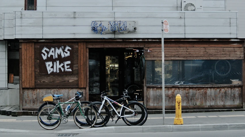 two bikes parked in front of a bike store on the street