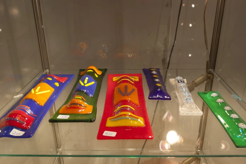 five colorful  wheels sit on a glass shelf