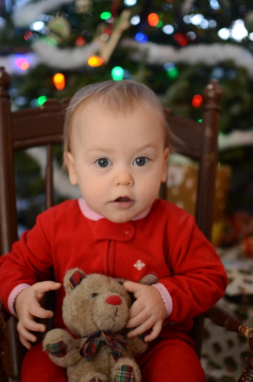 a baby holding a teddy bear on top of a chair