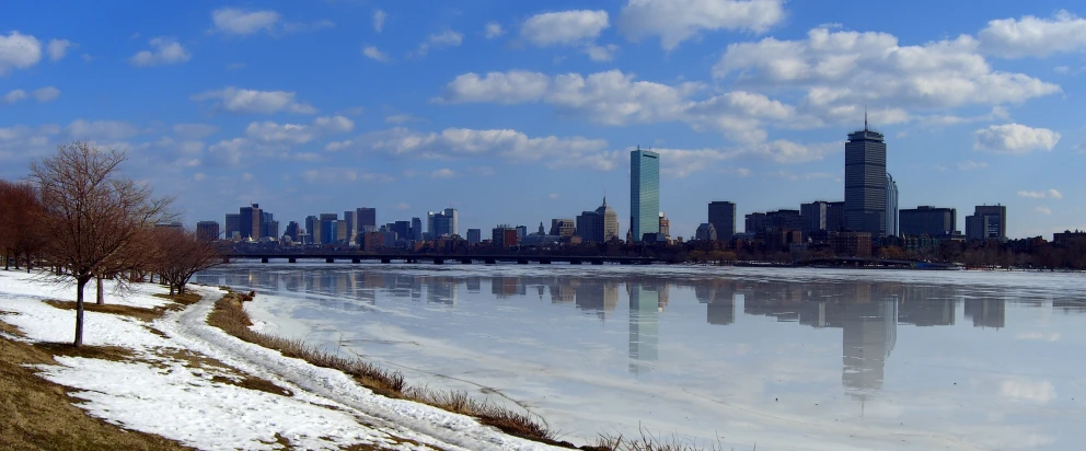 a city sits on the edge of a lake with snow covered banks