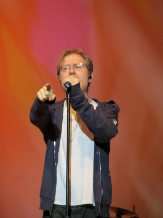 a man standing on stage with a microphone in his hand