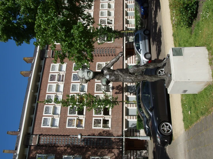 a statue in the street by cars parked in front of a el