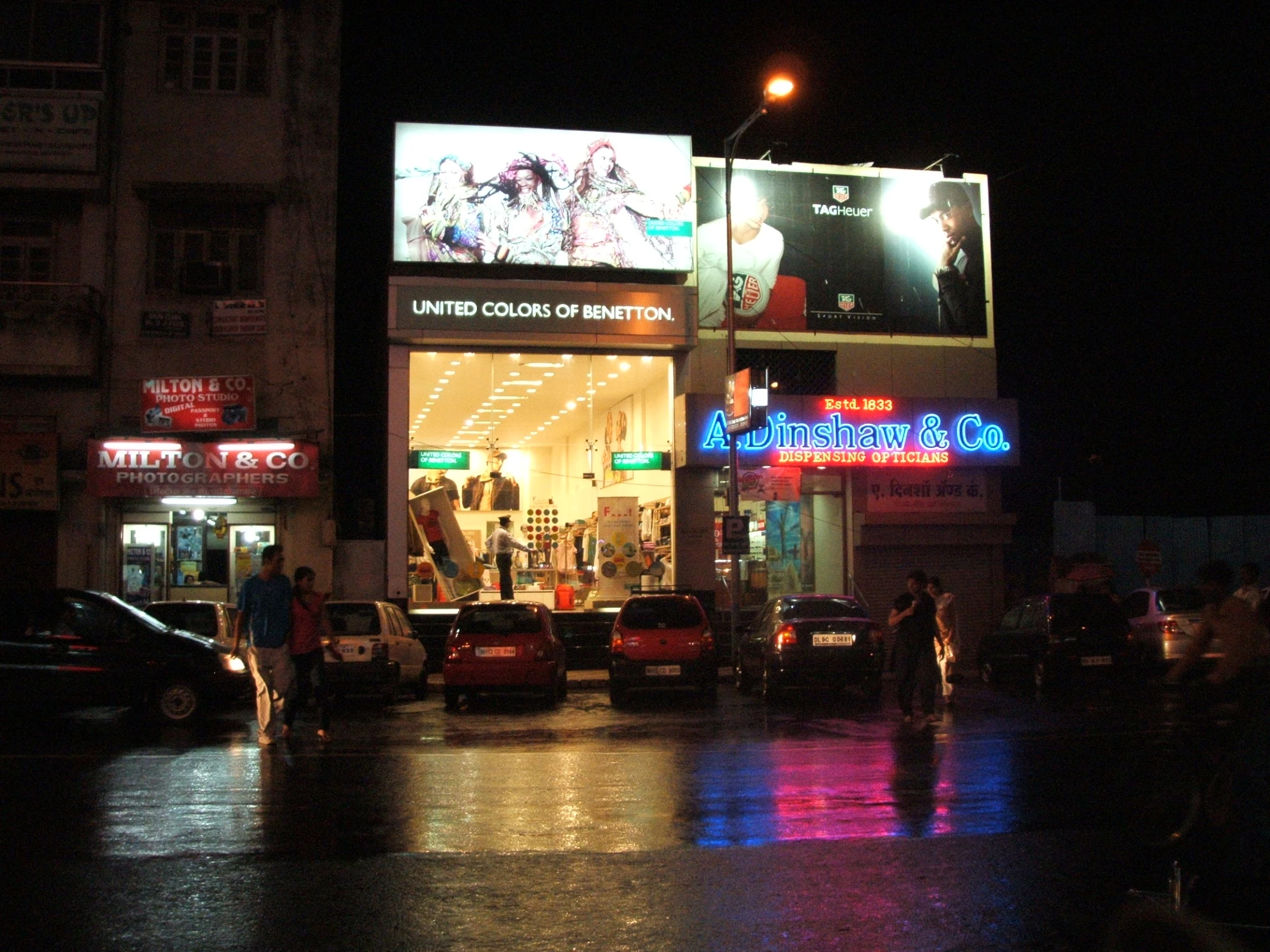 the city lights shine brightly at night as pedestrians cross the street