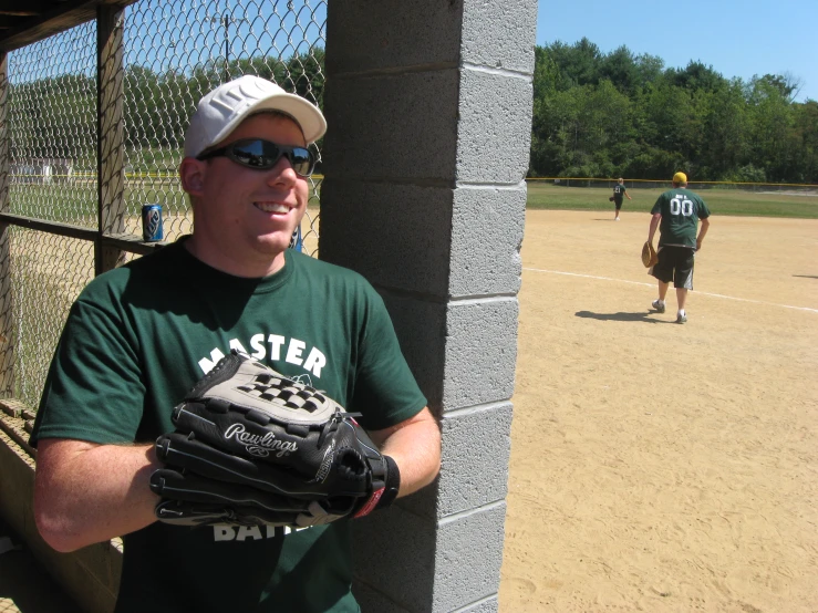 a man in a baseball hat and green shirt is holding a glove