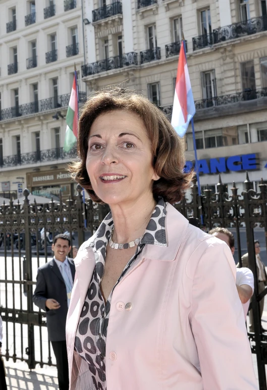 the smiling woman poses in front of a building