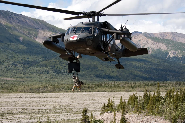 an army helicopter dropping supplies into the air