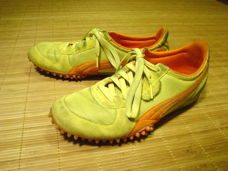 an orange pair of sports shoes on a wooden floor