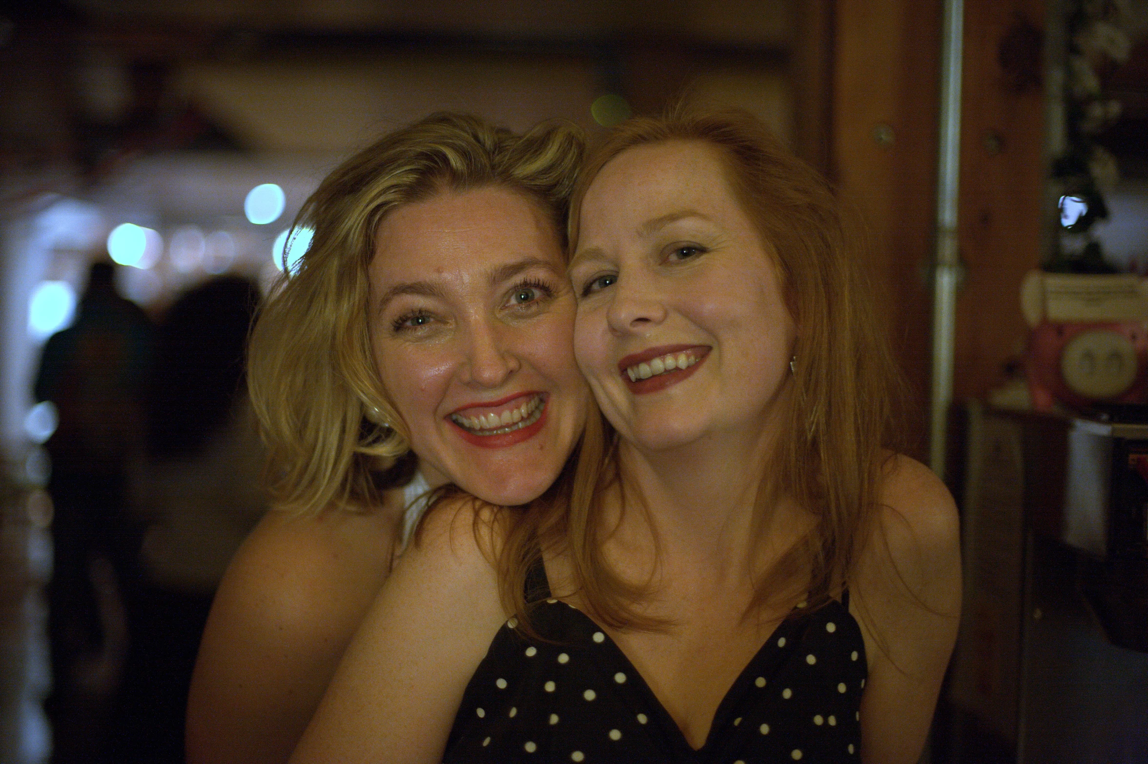 two smiling women standing in front of a camera