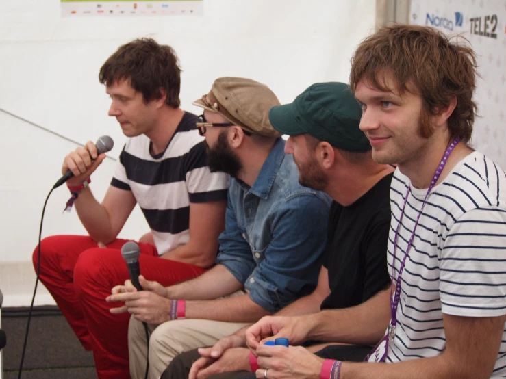 a group of people sitting next to each other holding microphones