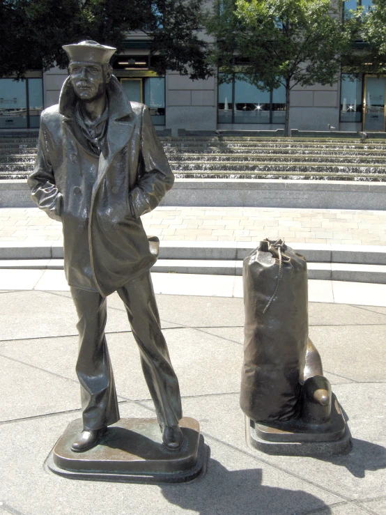 there is a statue on the street near a trash bag