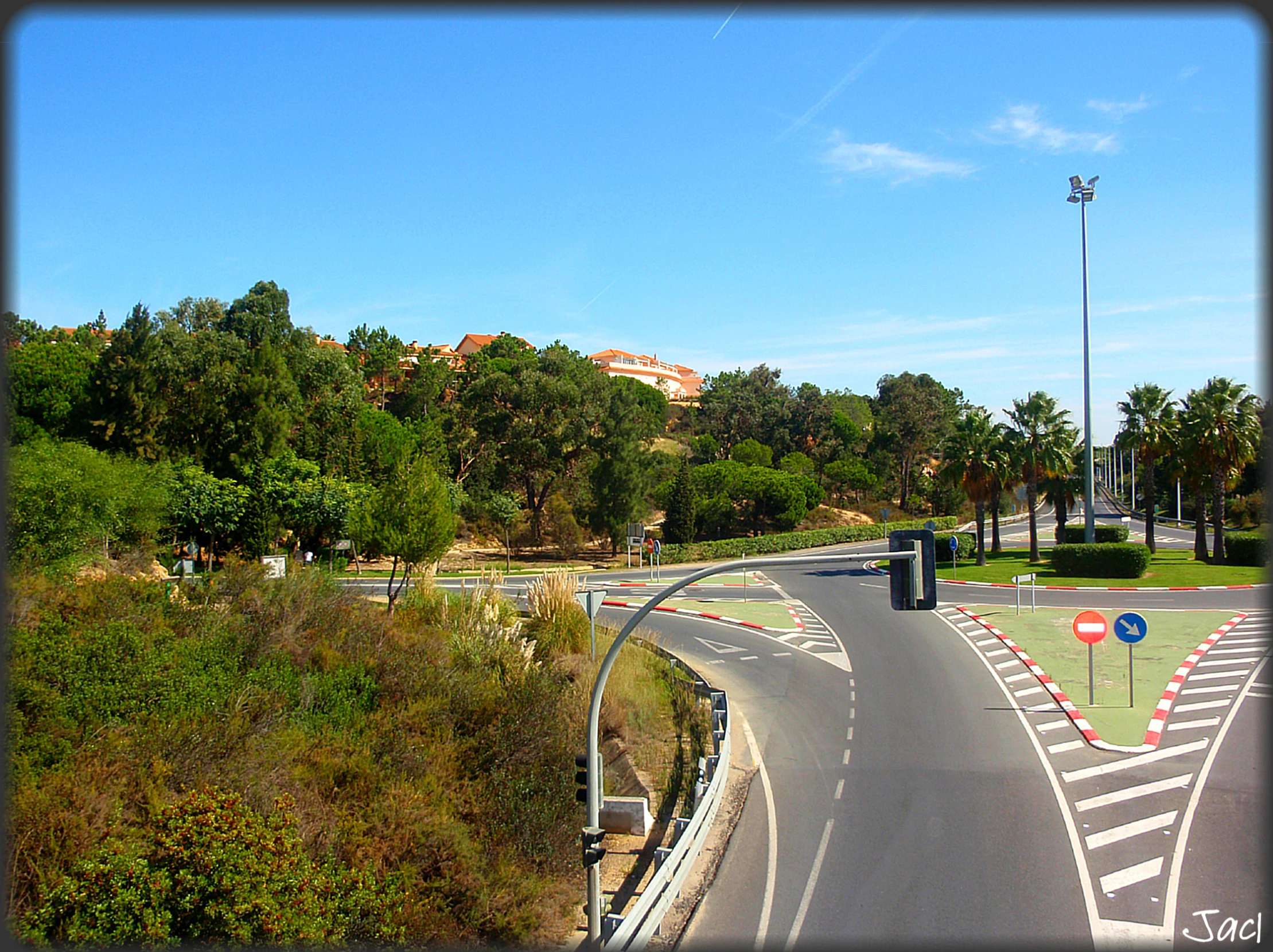 a winding road in front of green trees and a blue sky