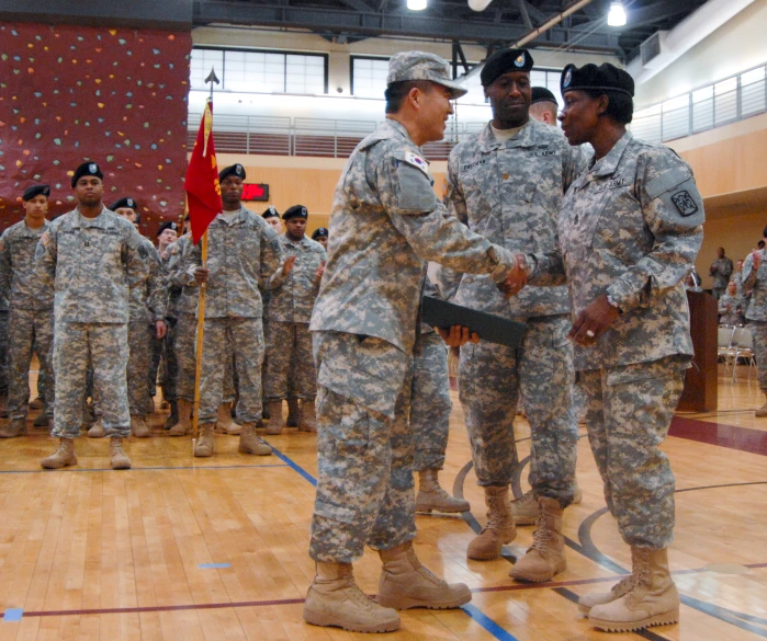 four military officers in uniform shake hands with one another