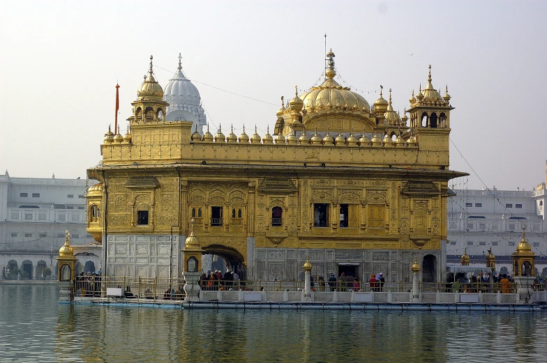 an ornate yellow building is seen by a lake