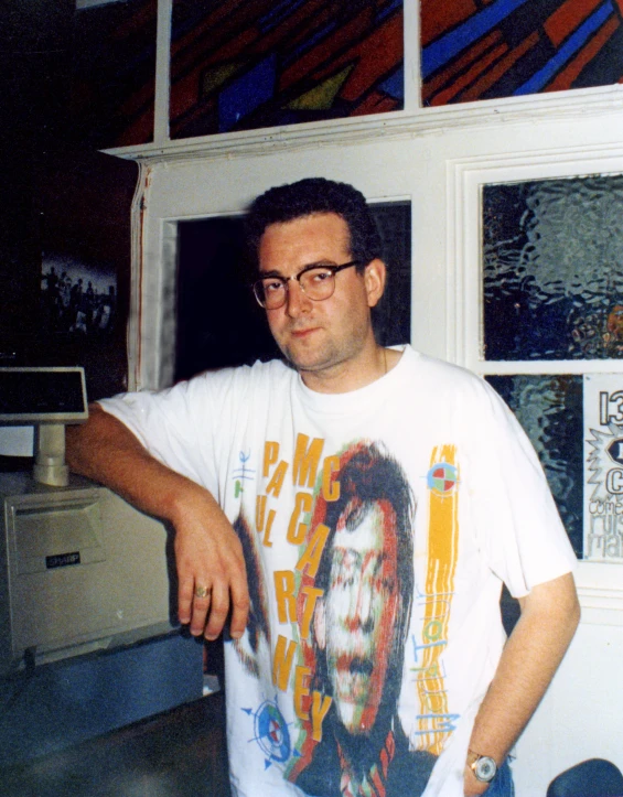 a man in glasses leaning against a window with a clock