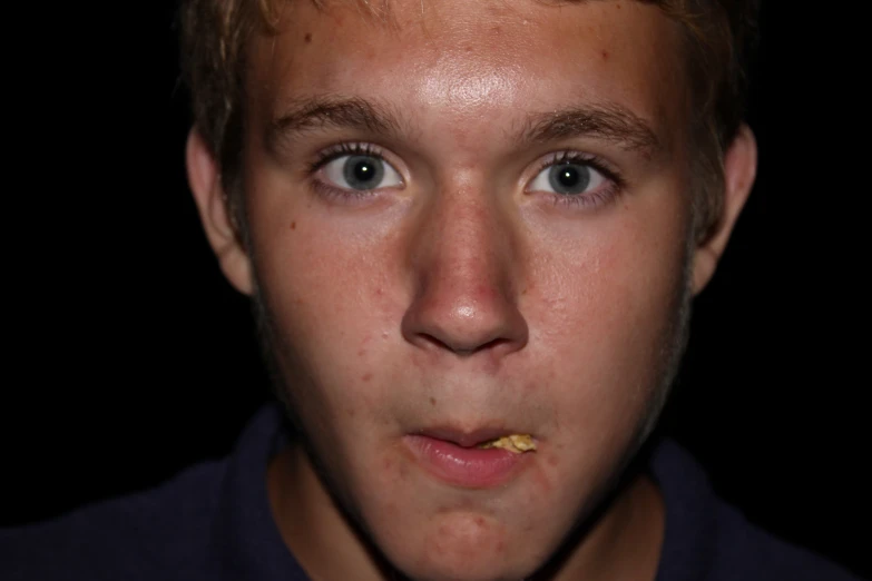 a close up po of a boy eating soing yellow