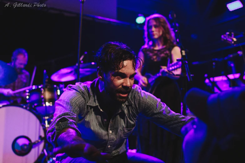 a band performs on a stage with purple lights