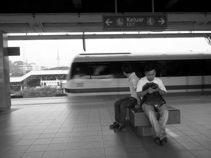 two people on a bench in front of a train