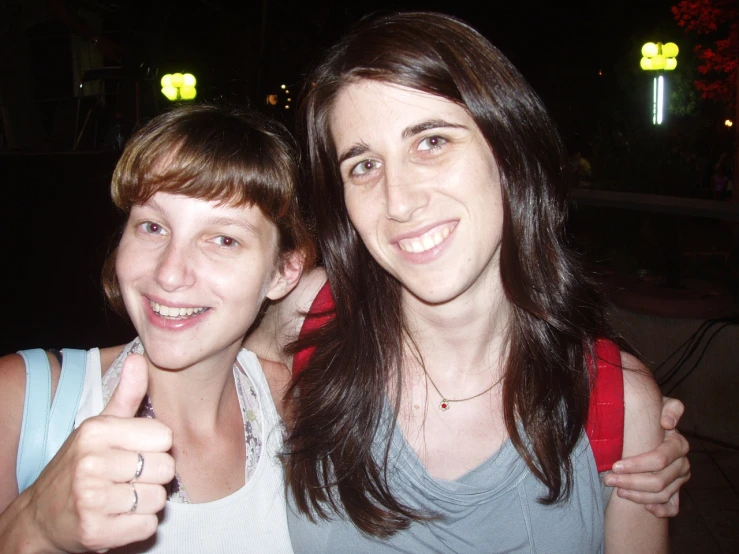 a woman in front of another smiling woman with an ok sign