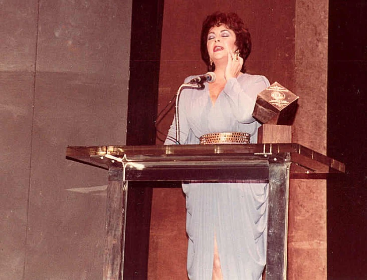 the woman stands at a podium while talking on her phone