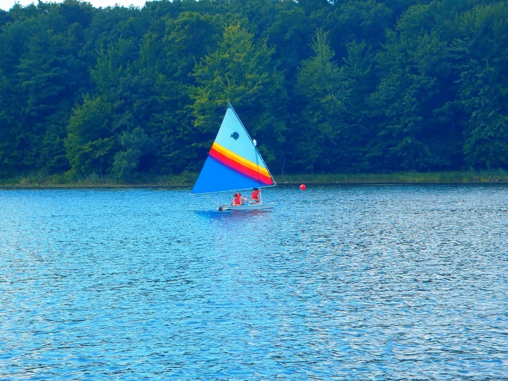 colorful triangular shaped boat floating in lake surrounded by trees