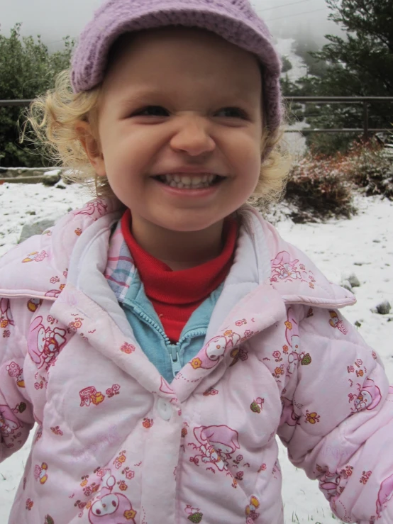 small child wearing pink jacket in winter with snow
