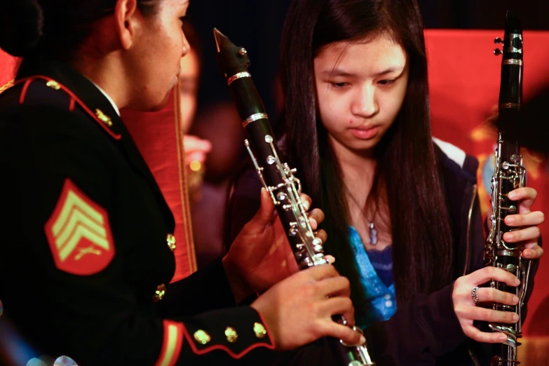 girl playing a flute while her marching band member looks on