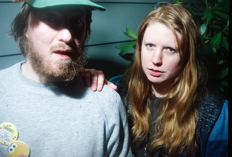 a woman and man stand in front of a house